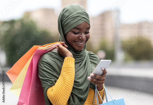 Taxi App. Black Muslim Woman Ordering Cab Outdoors Via Application On Smartphone photo