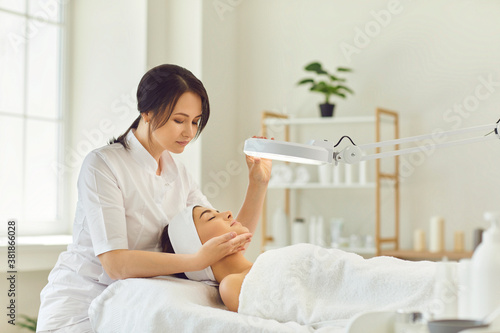 Smiling dermatologist looking at young womans face during skin examination