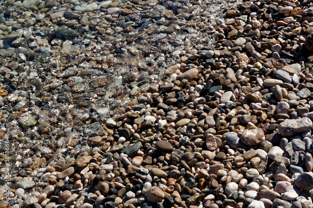 Kieselsteine an Kieselstrand, halb überspült, halb nass, teilweise trocken Kieselsteine an Kieselstrand, halb überspült, halb nass, teilweise trocken