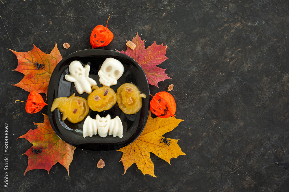 Halloween food. Funny jelly in the shape of pumpkin, skull and cast. A dark background and a place for text.