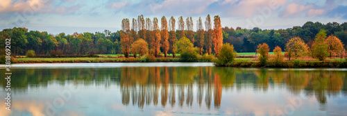 Trees and clouds reflections on a pond in autumn, panoramic landscape in Burgundy, France