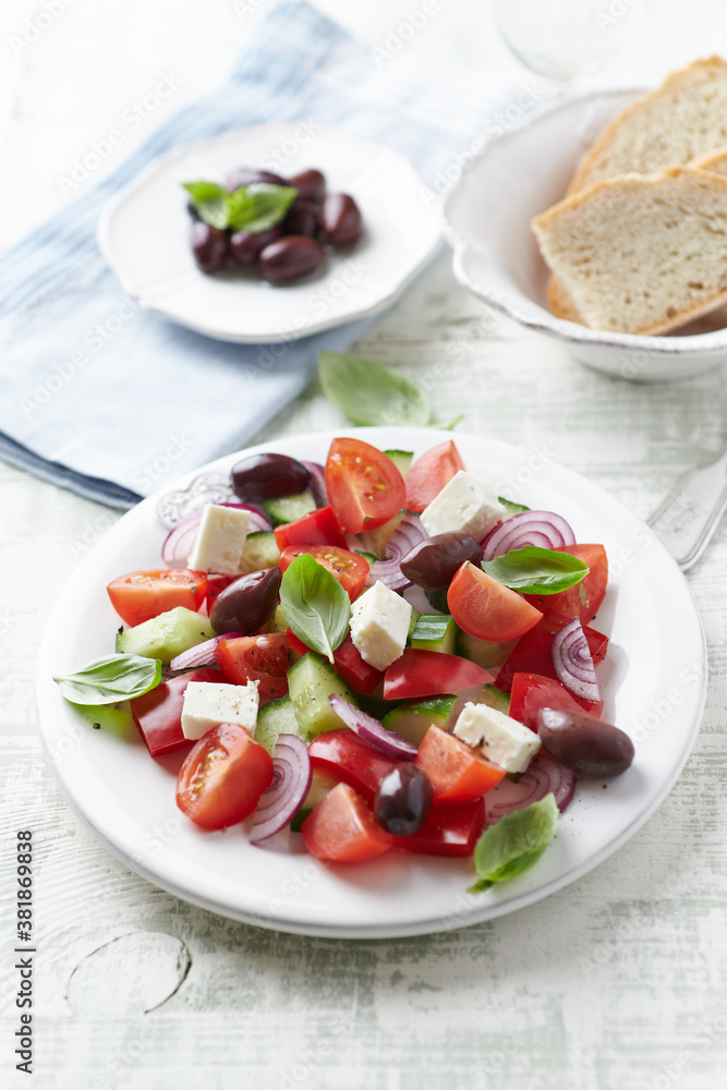 Simple salad with cherry tomatoes, feta cheese, kalamata olives, red pepper and fresh herbs. Bright wooden background. Close up. Simple salad with cherry tomatoes, feta cheese, kalamata olives, red pepper and fresh herbs. Bright wooden background. Close up.