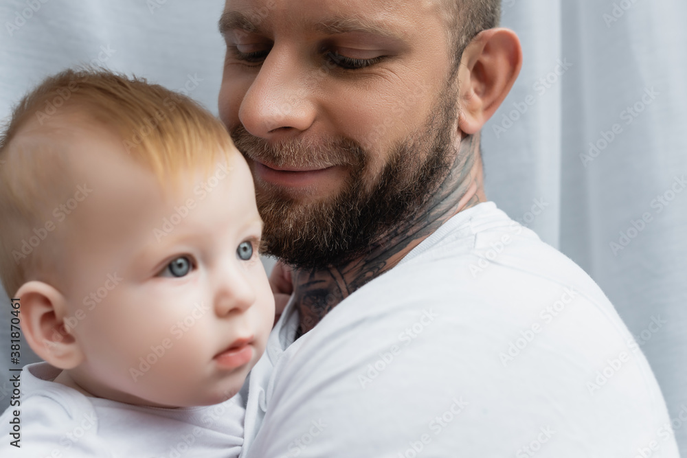 selective focus of joyful bearded man holding infant son in hands selective focus of joyful bearded man holding infant son in hands