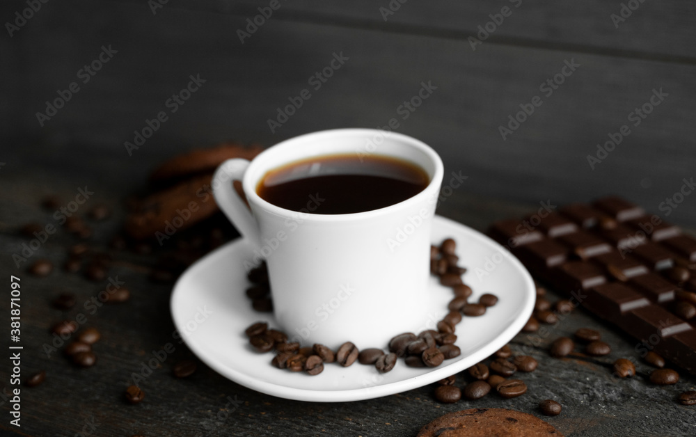 Coffee cup with cookies and chocolate on wooden table background. Mug of black coffee with chocolate cookies. Fresh coffee beans.