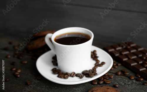 Coffee cup with cookies and chocolate on wooden table background. Mug of black coffee with chocolate cookies. Fresh coffee beans.