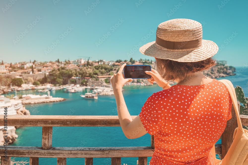 female travel blogger takes high-quality pictures of the sea coast in a small resort town while on vacation.