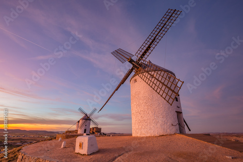 Beautiful white spanish windmill on the hill at fairy blue pink gold sunset near the castle in Consuegra, Toledo province, Spain