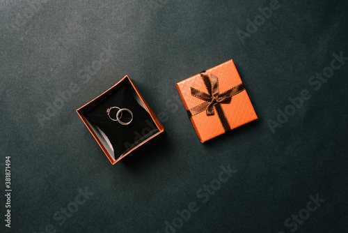 Wedding rings in a box on a dark background. Open brown box with the bride and groom's rings. Wedding concept. Top view, flat layout