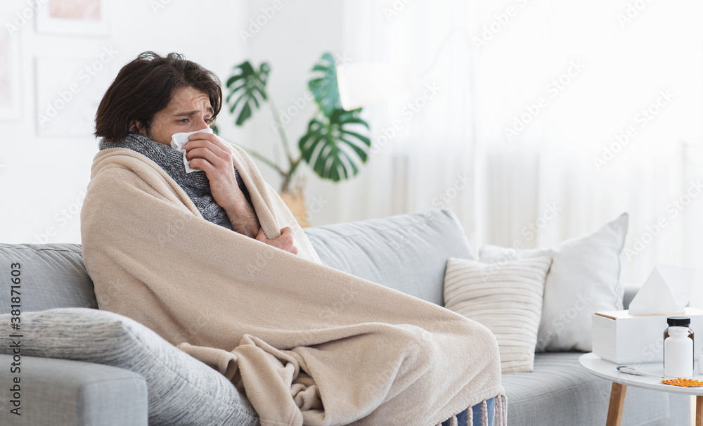 Sick man covered in blanket sneezing his nose Sick man covered in blanket sneezing his nose
