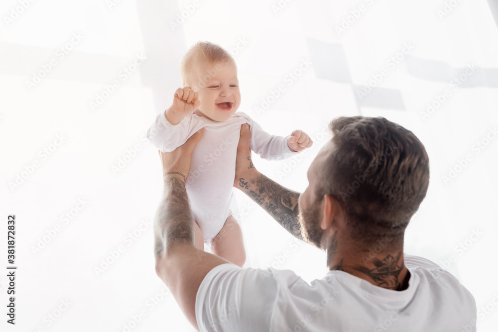 back view of young father holding excited baby boy in outstretched hands back view of young father holding excited baby boy in outstretched hands