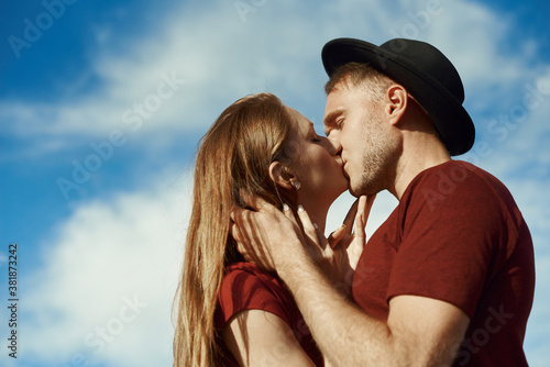 A couple is kissing outdoor. The young man and woman is kissing against the sky © etonastenka