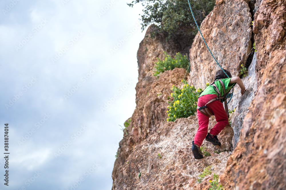 The child is climbing on a natural terrain. The child is climbing on a natural terrain.