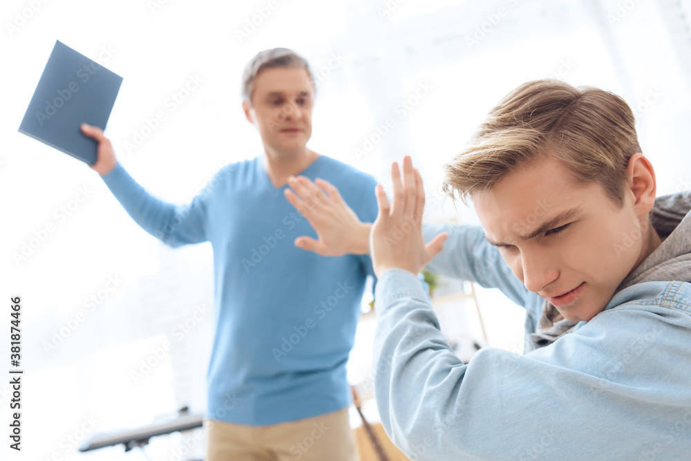 Obraz premium Father swings to hit his son with book.