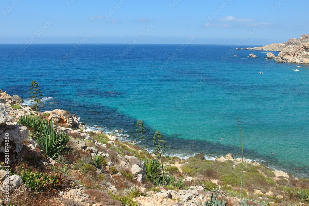 Golden bay beach on Malta island with beautiful blue sea water and rocky coastline in bright sunny day