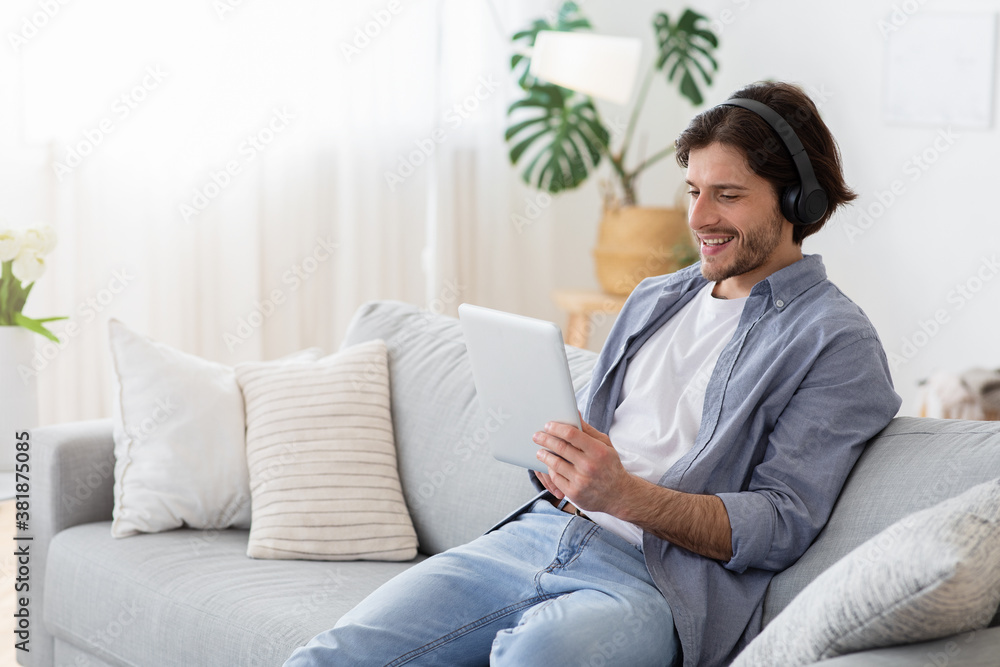 Happy guy with wireless headset and digital tablet at home Happy guy with wireless headset and digital tablet at home