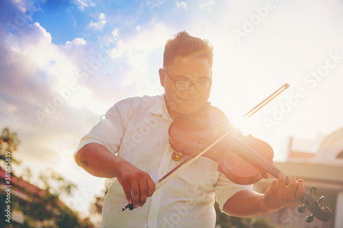A musician fat man is practicing the violin playing with the melodiousness. Selected focus.