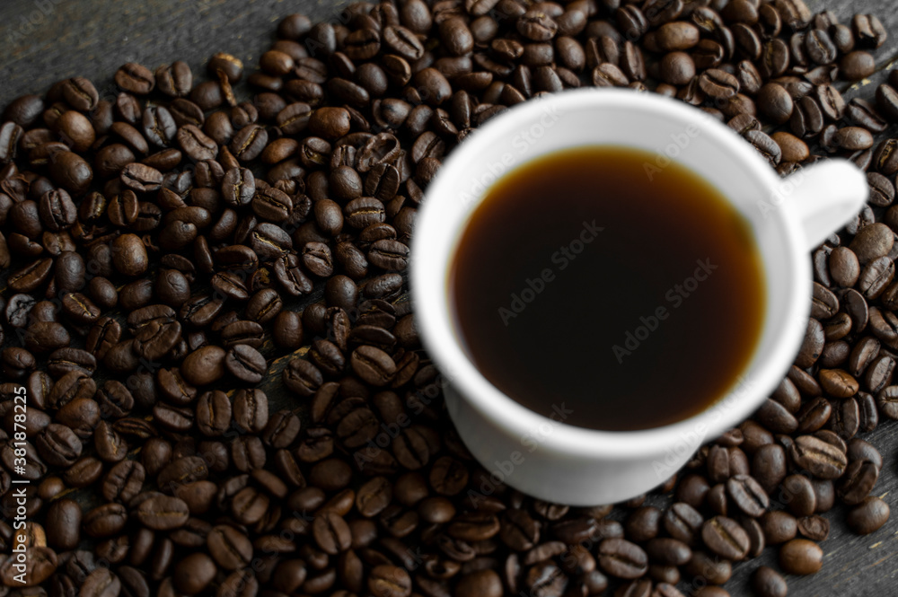 White cup of coffee with roasted coffee beans background. Mug of black coffee. White cup of coffee with roasted coffee beans background. Mug of black coffee.