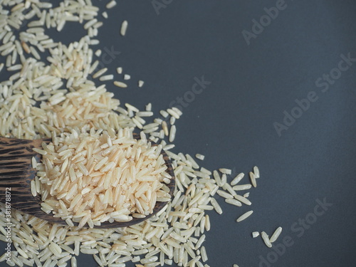 Coarse brown jasmine rice ( milled rice imperfectly cleaned, unpolished or half milled rice ) on black background, Healthy food and diet concept.
