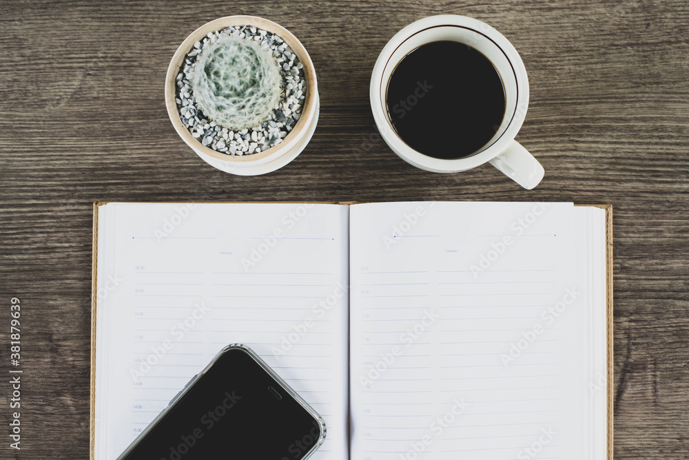 Naklejka premium Book, cactus and coffee cup placed on a wooden table, Top view.