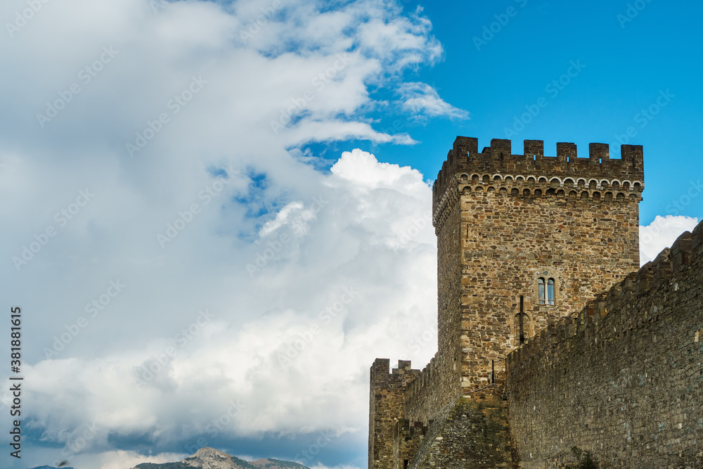 The square tower of an ancient fortress on a background of blue sky with clouds. The square tower of an ancient fortress on a background of blue sky with clouds.
