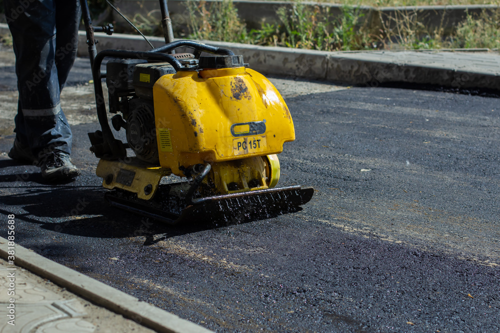 Obraz premium Vibratory plate for asphalt. Pothole repair process. Asphalt compaction machine. New asphalt