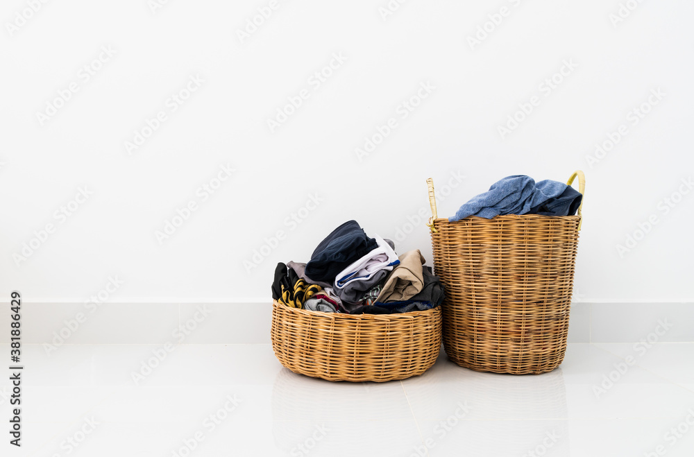 Different shapes of wicker basket full of laundry clothes in clean white wall background inside bedroom. Different shapes of wicker basket full of laundry clothes in clean white wall background inside bedroom.