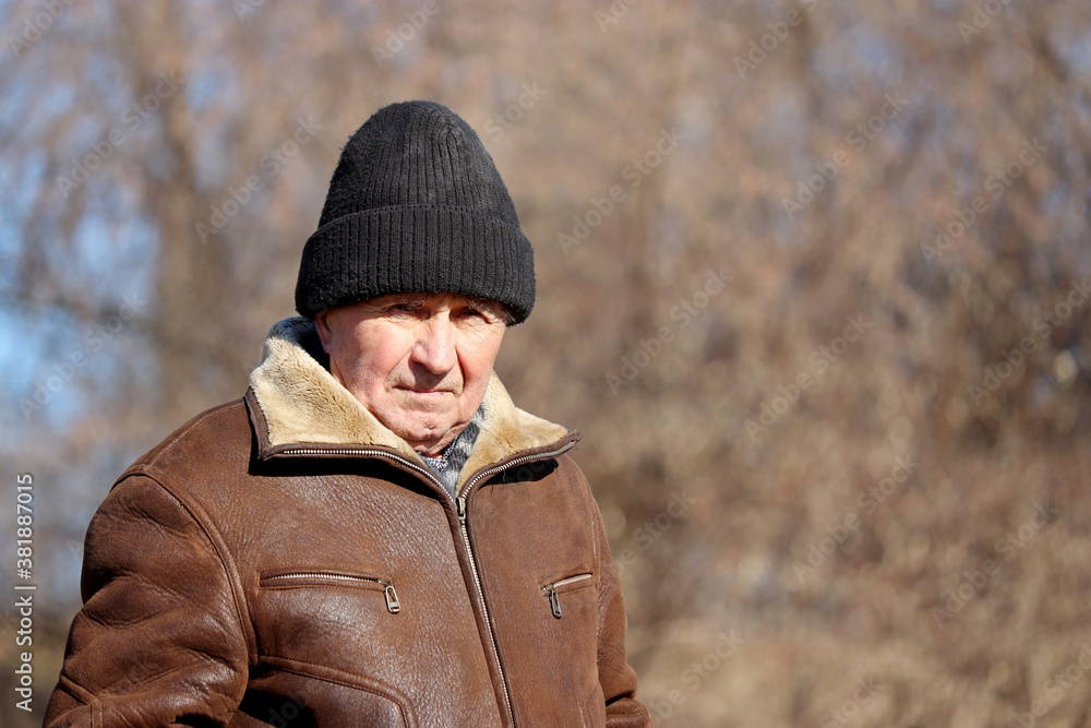 Portrait of elderly man standing in autumn park. Concept of old age, life in village
