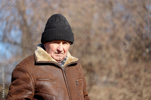 Portrait of elderly man standing in autumn park. Concept of old age, life in village © Oleg