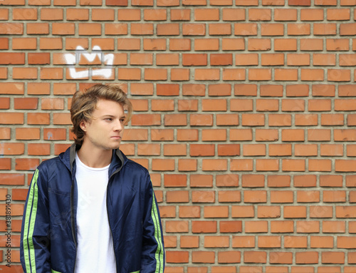Like a king.  Attractive teenage boy standing against brick wall background © lado2016