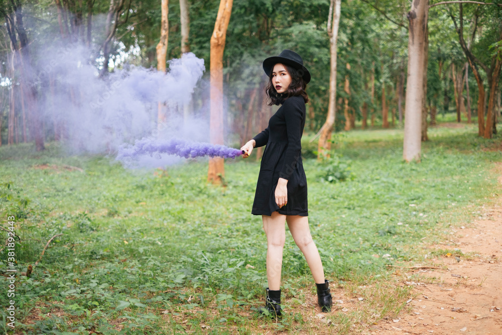 Portrait of asian black witch with purple smoke torch in deep forest - halloween theme. Portrait of asian black witch with purple smoke torch in deep forest - halloween theme.