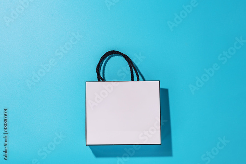 Empty white shopping bag on blue background, top view