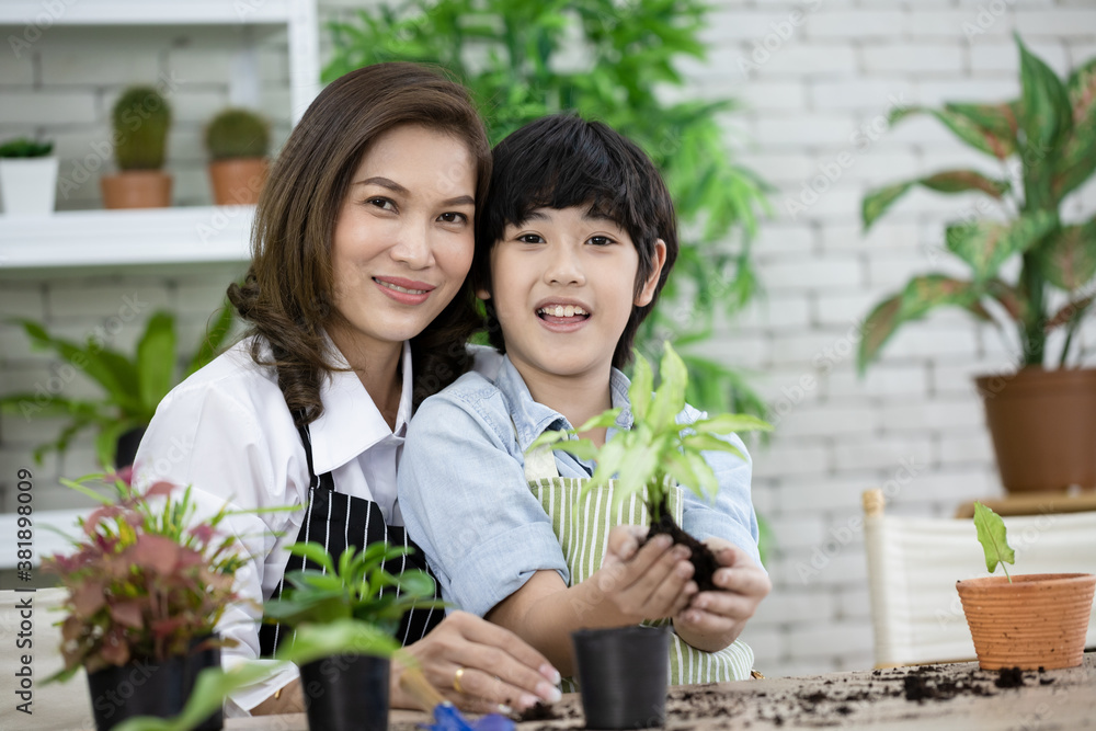Cute boy helps her mother to care for plants in the morning. Mom and her son engaged in gardening. Happy family day. play and learning concept. Soft focus and blur