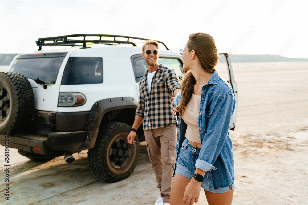 Young happy loving couple outdoors at beach near car walking Young happy loving couple outdoors at beach near car walking