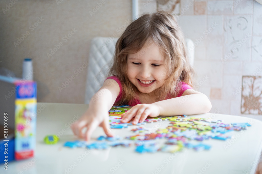 little girl with light wavy hair collects a puzzle at home and has fun. little girl with light wavy hair collects a puzzle at home and has fun.