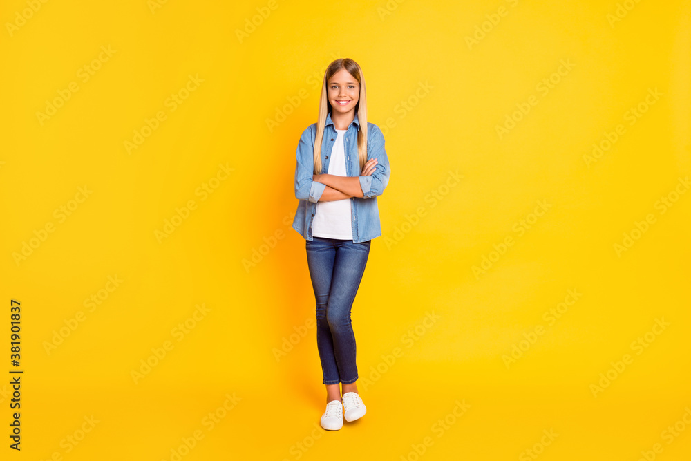 Full length body size photo of schoolgirl with straight blonde hair keeping hands crossed isolated on bright yellow color background Full length body size photo of schoolgirl with straight blonde hair keeping hands crossed isolated on bright yellow color background