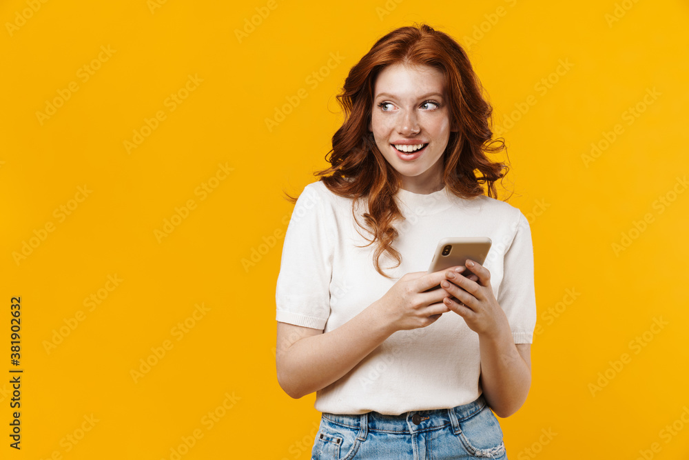 Image of ginger happy girl smiling and using mobile phone Image of ginger happy girl smiling and using mobile phone