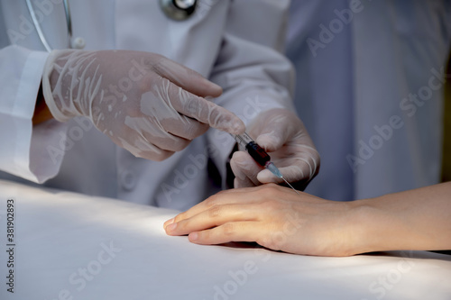 The doctor's hand was using a syringe to take a sample of blood from a patient