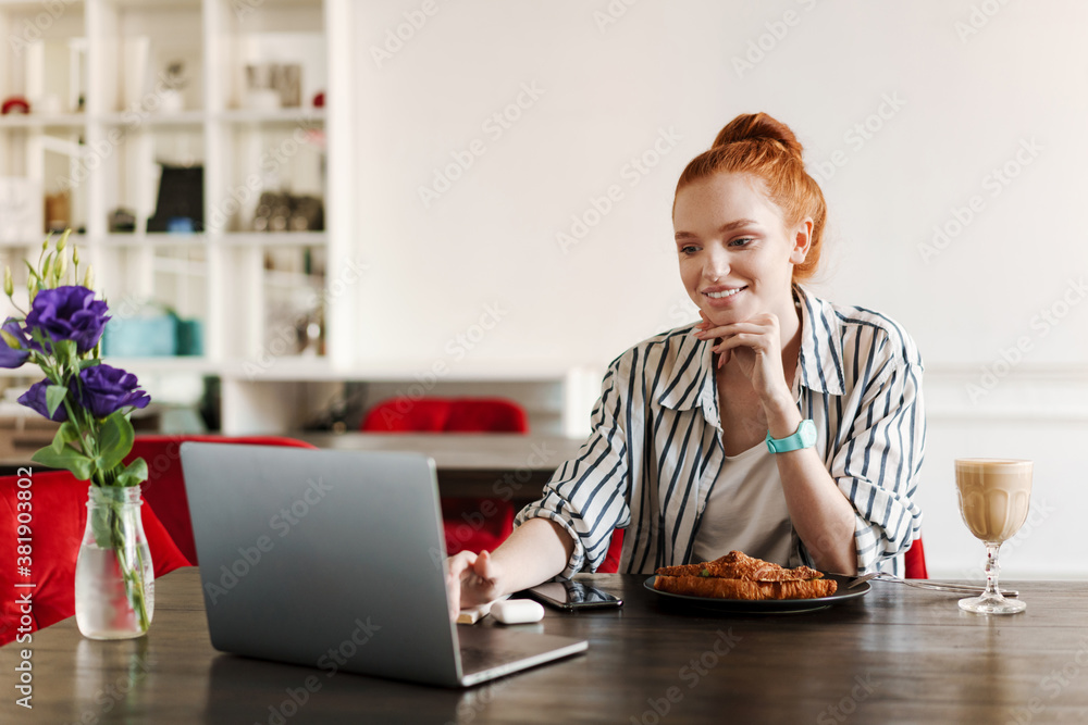 Attractive young redheaded woman using laptop Attractive young redheaded woman using laptop