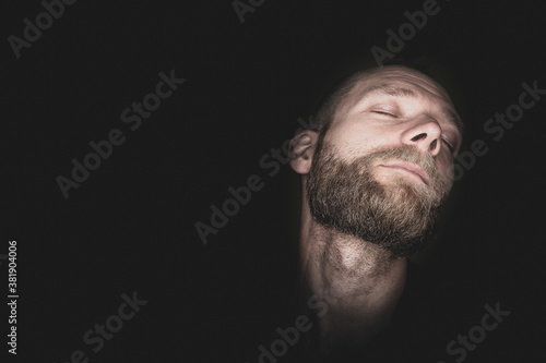 A young man lasciviously pulls his head back and has his eyes closed.