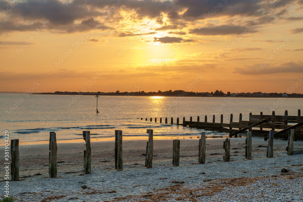 Sunset at East Head, West Wittering, Chichester Harbour, England. A golden sky and calm sea make a tranquil evening scene.
