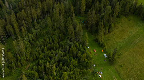 Tourist camp in a forest mountains. Many tents through the forest.