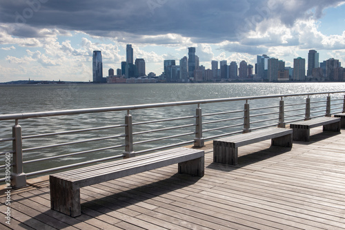 Row of Empty Benches on a Pier along the Hudson River in New York City with a view of the Jersey City Skyline © James