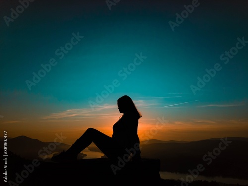 A woman sitting in profile at sunset