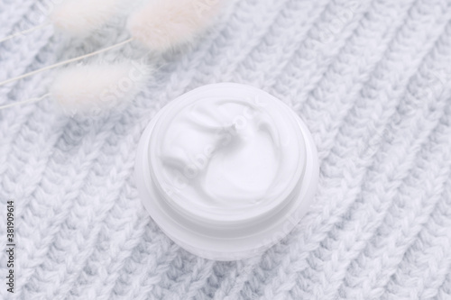 Open jar of cream top view. Grey background. Winter skin care cosmetics concept