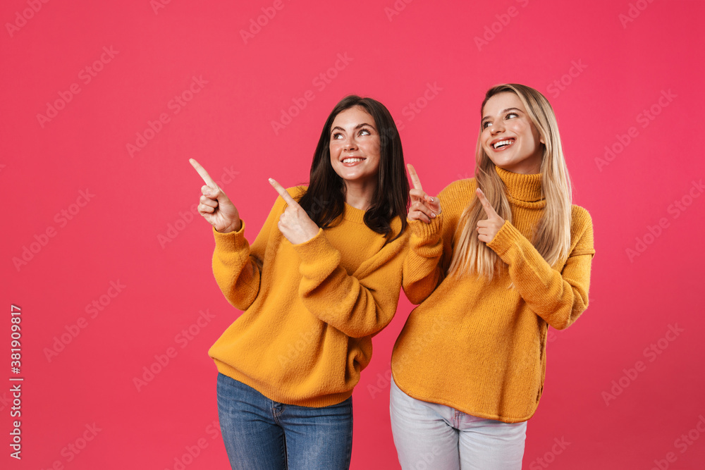 Image of joyful beautiful women smiling while pointing fingers upward Image of joyful beautiful women smiling while pointing fingers upward