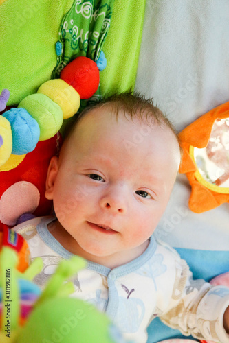 smiling happy cute child infant playing with toys on the play carpet close up baby face