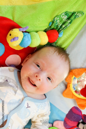 smiling happy cute baby child infant playing with toys on the play carpet