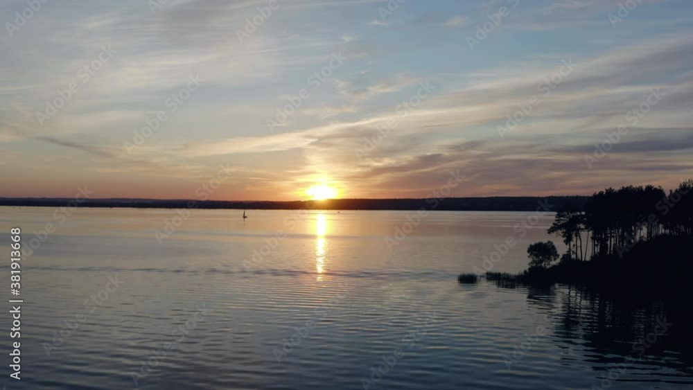 Fly over water towards the setting sun against the backdrop of the dark silhouettes of the island, fishing boats and sailing yachts. Fly over water towards the setting sun against the backdrop of the dark silhouettes of the island, fishing boats and sailing yachts.