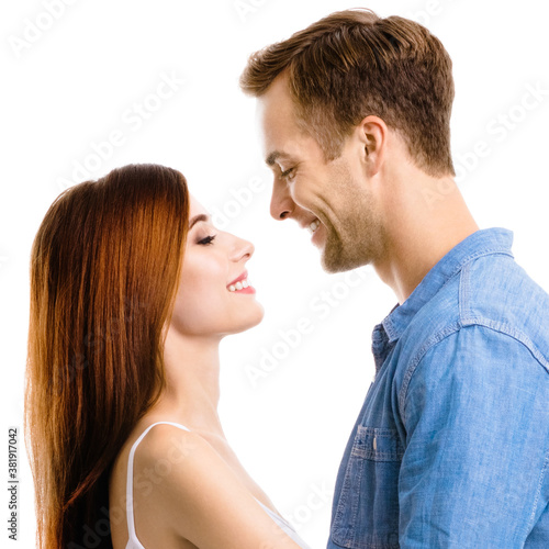 Profile side of smiling happy amorous couple. Portrait of standing close and looking at each other models in love studio concept, isolated on white background. Man and woman posing. Square composition
