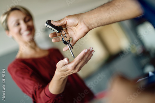 Close-up of woman receiving car keys in auto repair shop.
